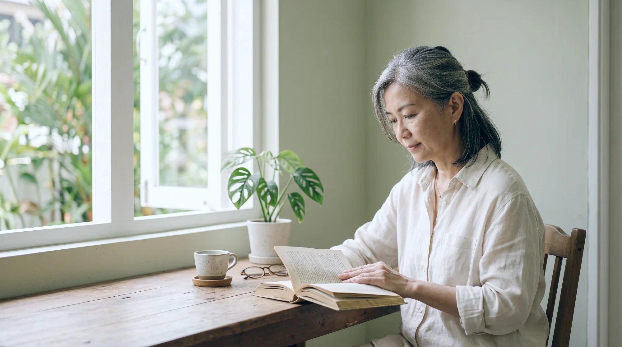 A woman in her fifties reading by a window
