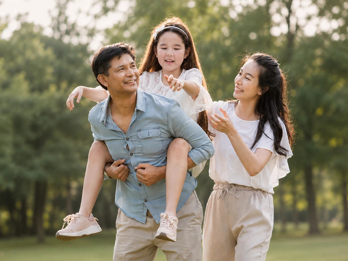 A family walking together in a park, a girl riding on her father's back